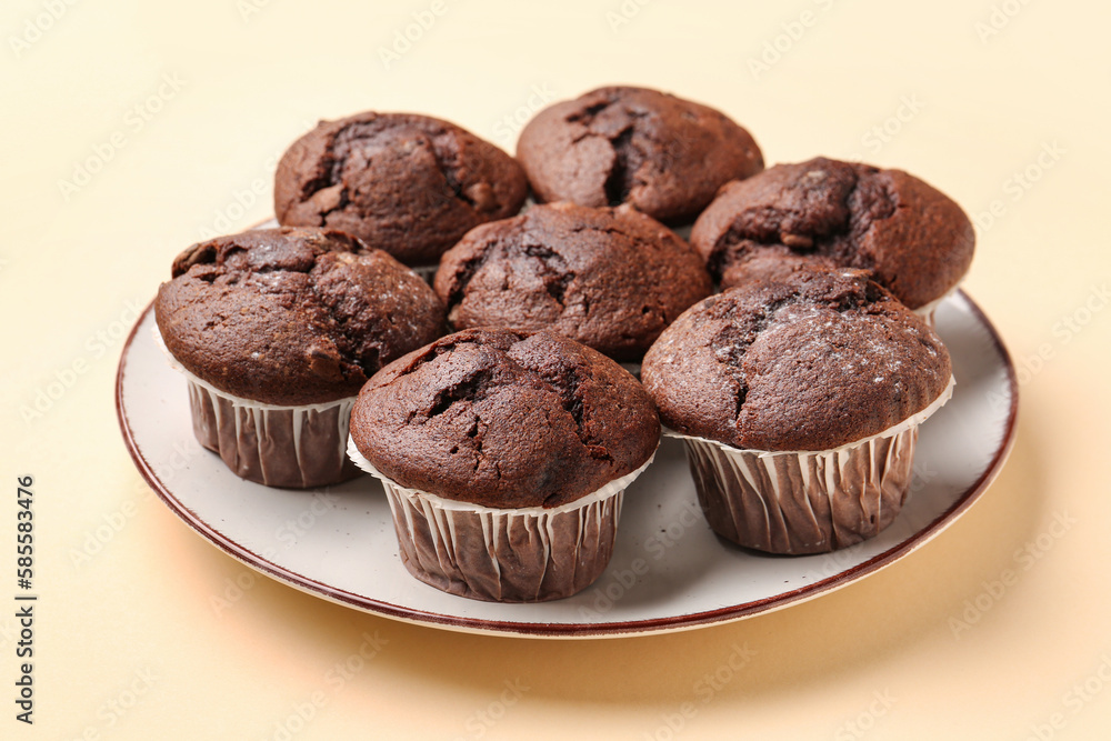 Plate with tasty chocolate cupcakes on beige background