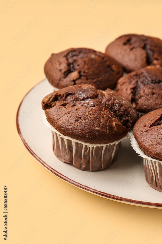 Plate with tasty chocolate cupcakes on beige background, closeup