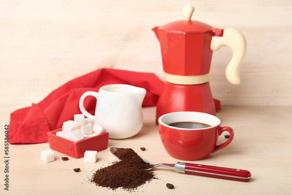 Spoon of coffee powder, sugar, milk jug, cup and maker on light wooden table