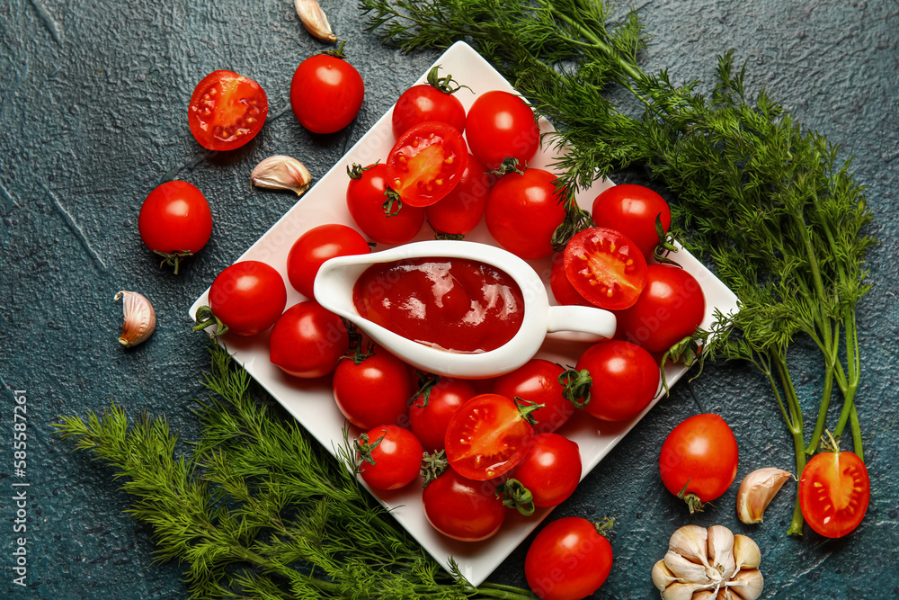 Gravy boat with tasty ketchup and fresh vegetables on dark background