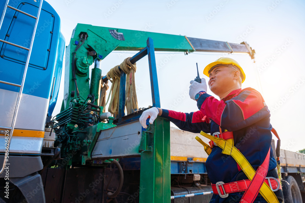 Asian supervisor or foreman with mobile crane at construction site.