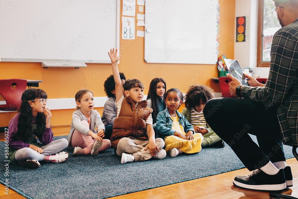 Boy raises his hand to answer a question in a classroom