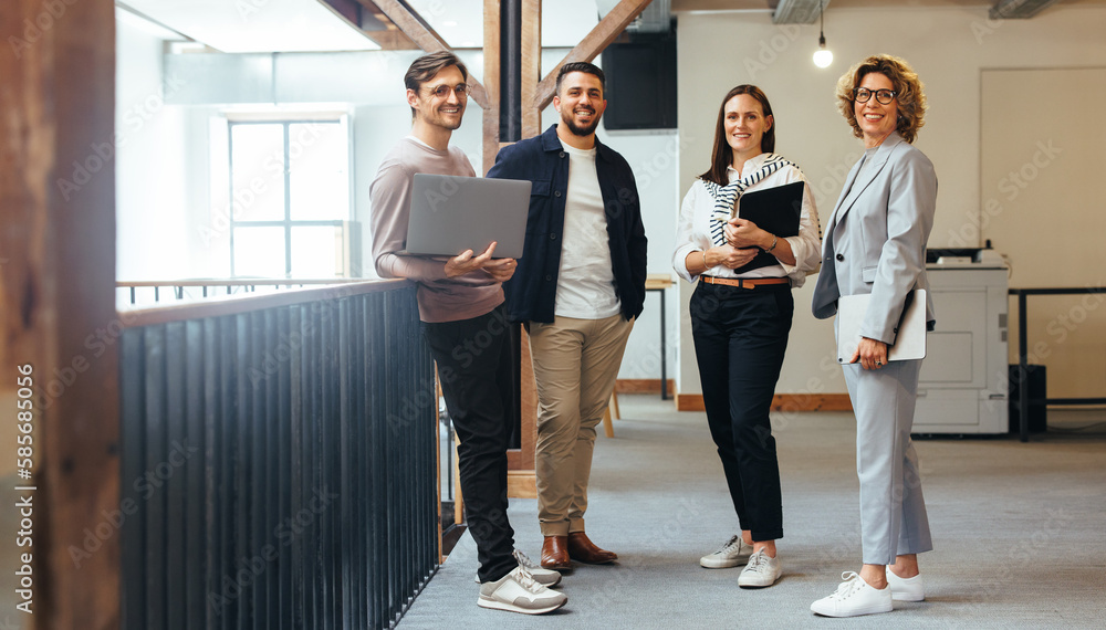 Group of tech professionals looking at the camera as they stand together in an office