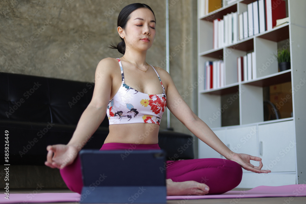 Beautiful asian woman doing relaxing exercise at home and practicing yoga in quiet living room.