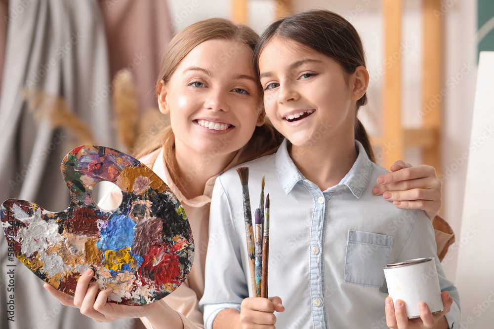 Little girl with paint brushes and her drawing teacher in workshop, closeup