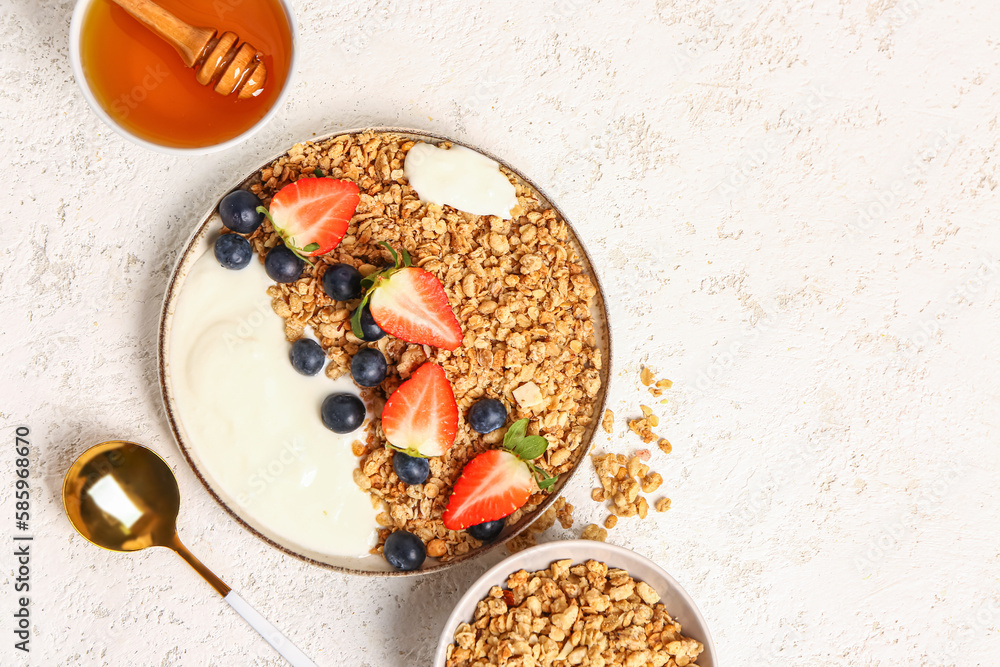 Plate of tasty granola with yogurt and berries on light background