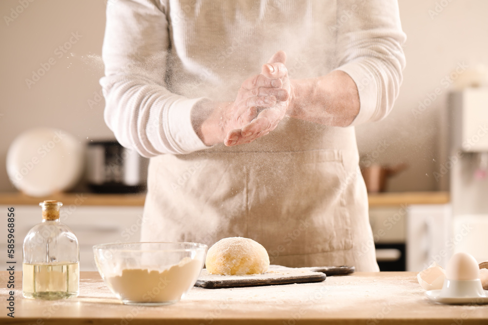 Male chef making dough for pasta at table in kitchen, closeup