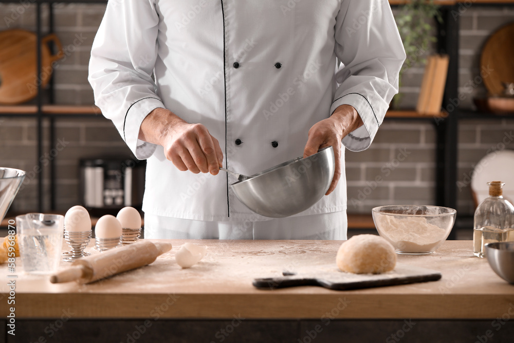 Male chef making dough for pasta at table in kitchen, closeup