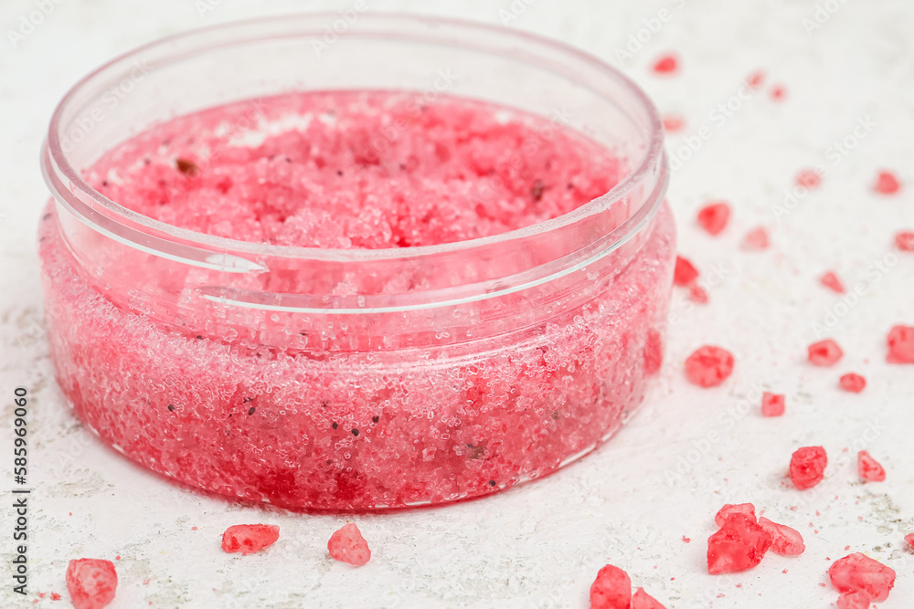 Jar of natural body scrub and sea salt on light background