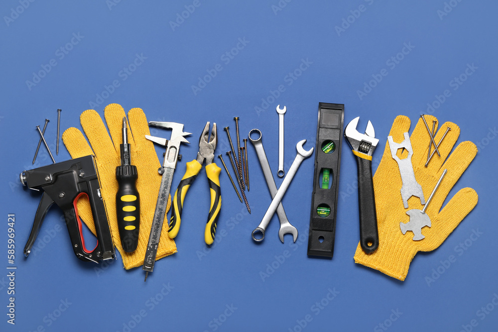 Different construction tools and gloves on blue background