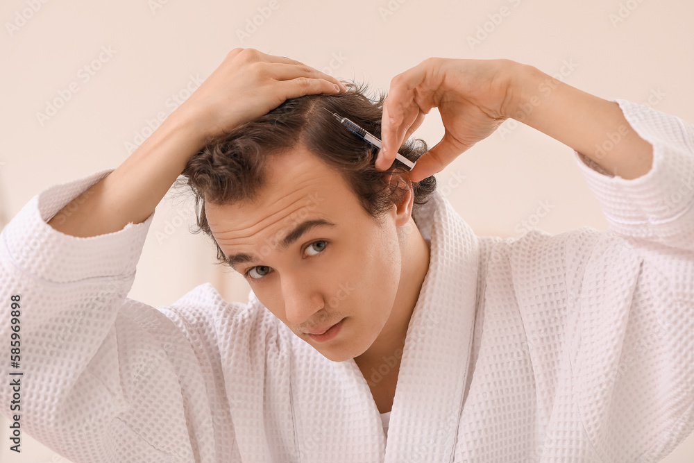 Young man with hair loss problem making injection in bathroom, closeup