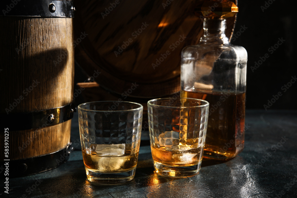 Wooden barrels, bottle and glasses of cold whiskey on dark background