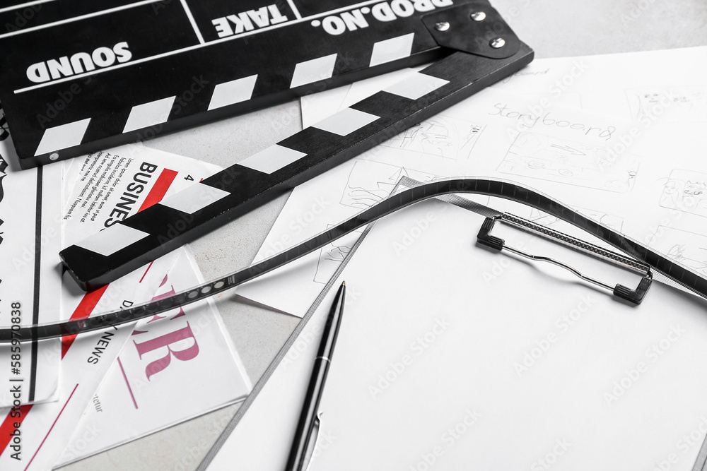 Clipboard with film, newspapers and movie clapper on light background