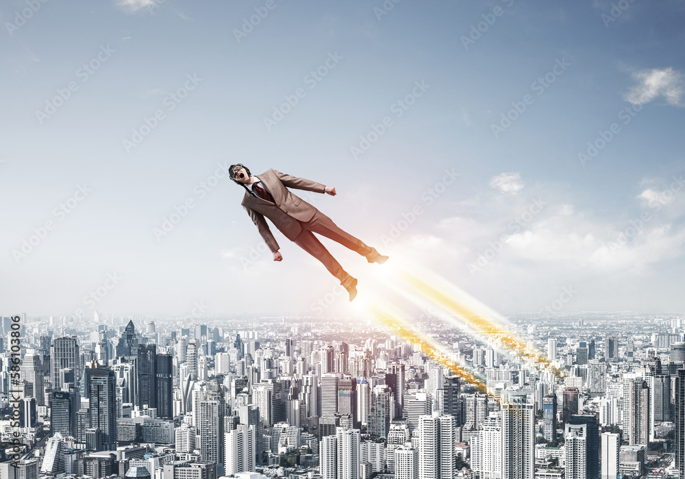 Businessman in suit and aviator hat flying in sky