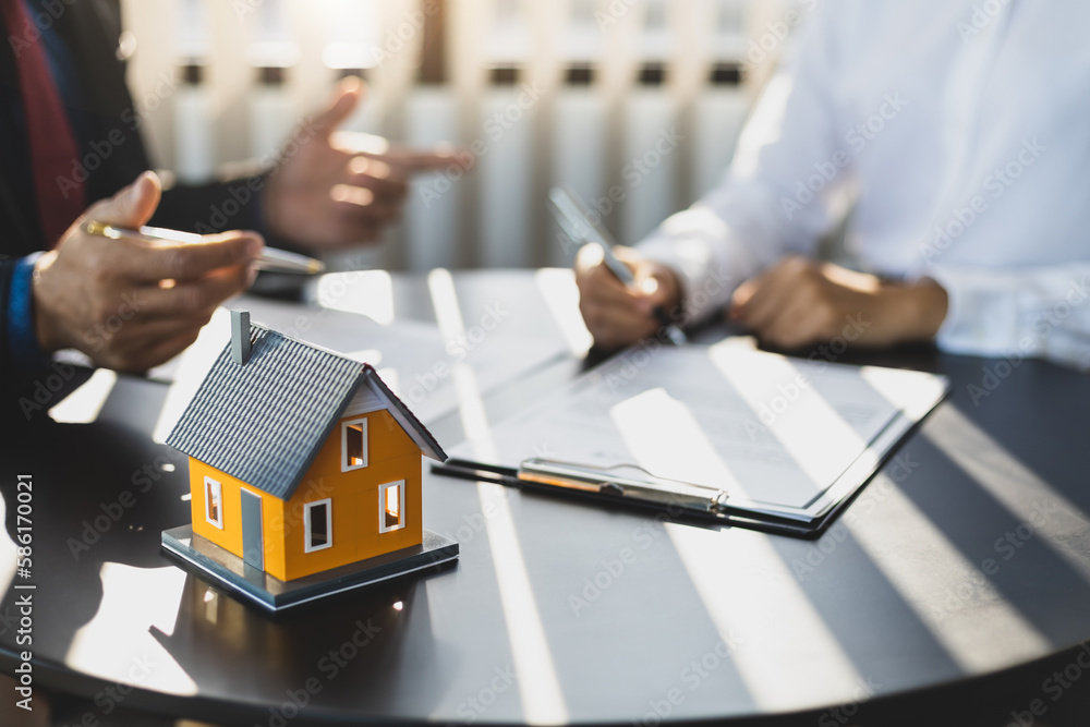 Businessman in suit in his office showing home insurance policy and pointing with a pen where the po