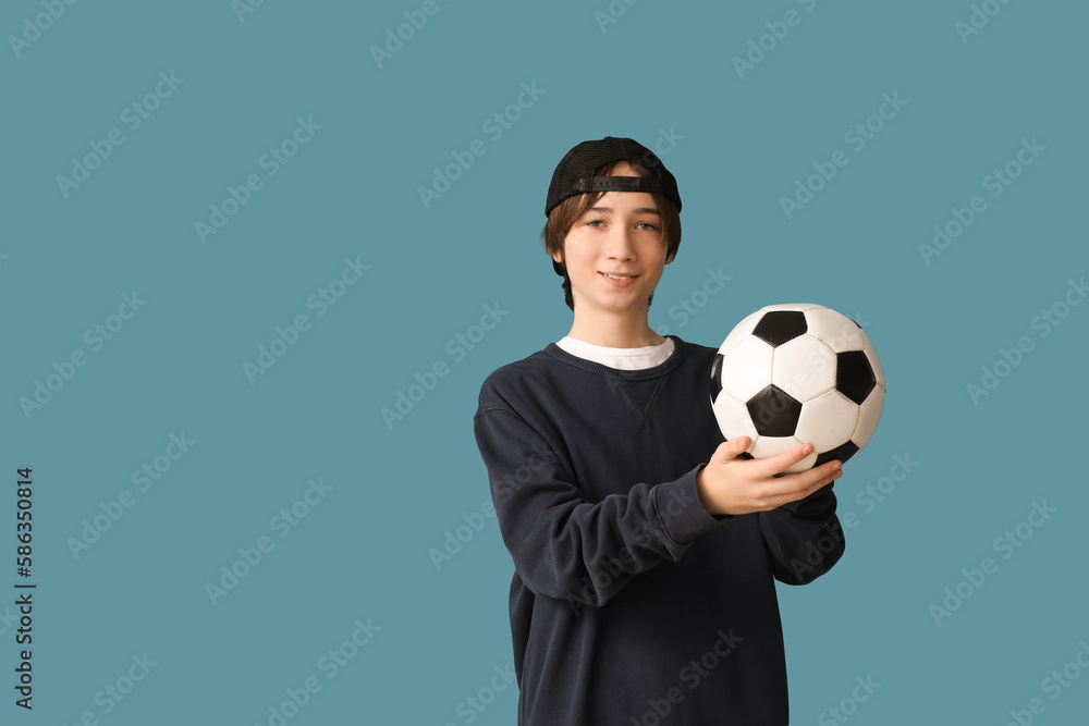 Teenage boy with soccer ball on blue background