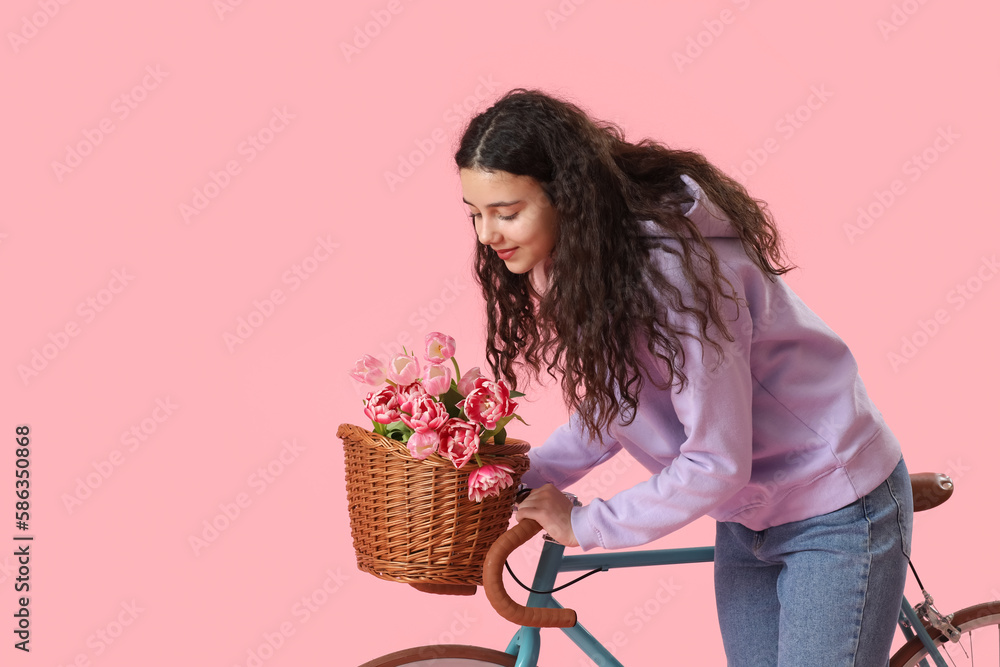 Teenage girl with bicycle and flowers on pink background