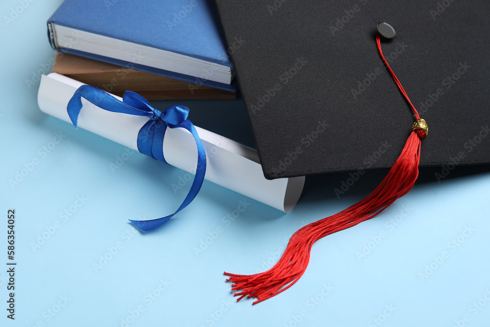 Diploma with ribbon, graduation hat and books on blue background