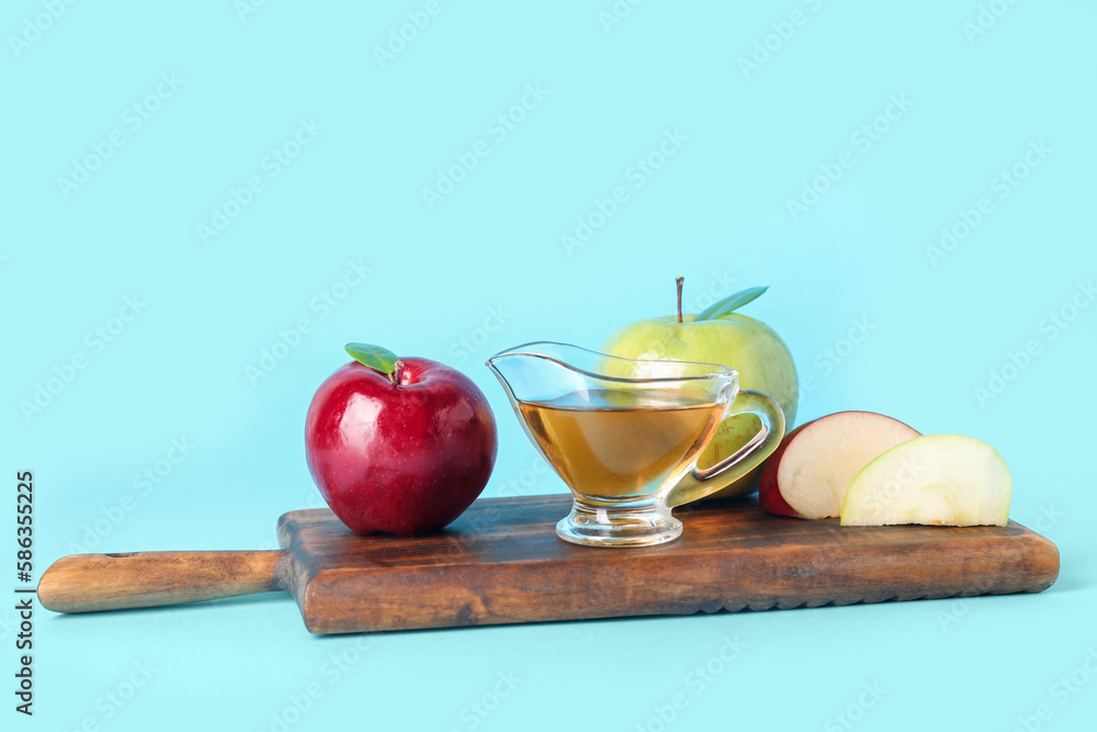 Gravy boat with fresh apple cider vinegar and fruits on blue background