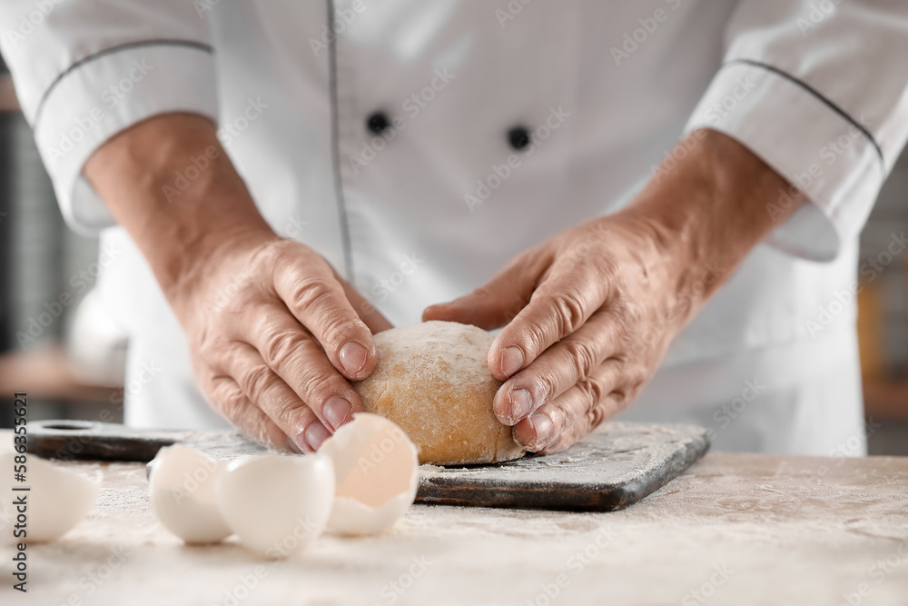 Male chef preparing dough for pasta at table in kitchen, closeup