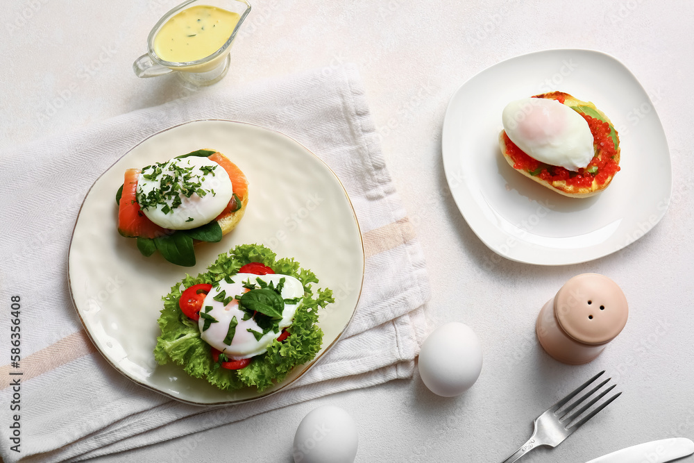 Plates with tasty eggs Benedict on white table