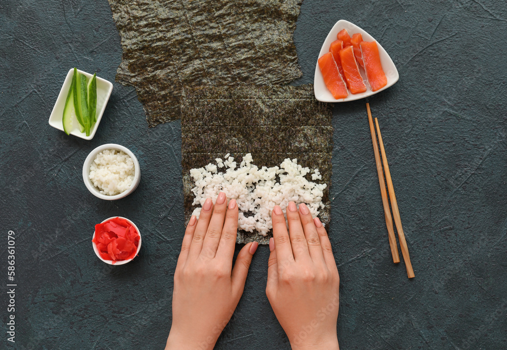 Woman preparing sushi rolls on dark background