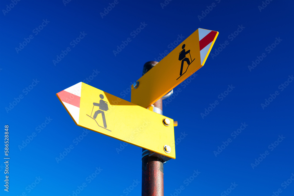 Hiking and traveling in the mountains. Directional marker for a mountain hike. Yellow bright sign wi