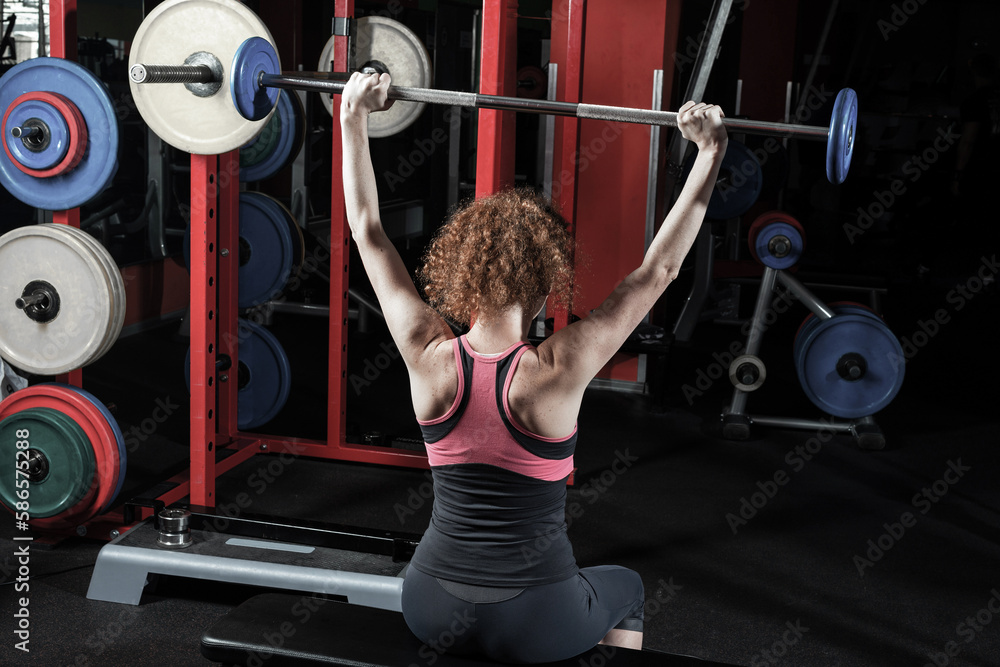 Woman bodybuilder engaged with a barbell in the gym