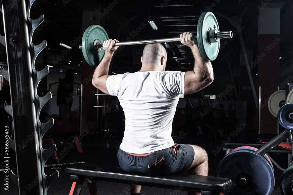 Male athlete lifts the barbell