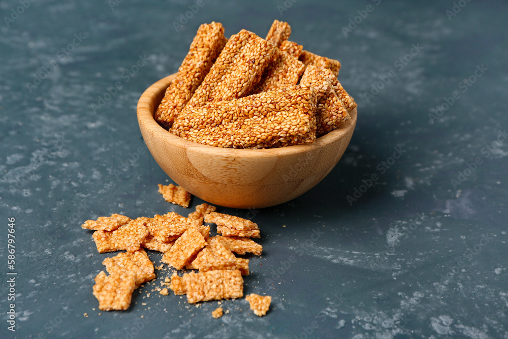 Bowl of tasty sesame kozinaki on blue background