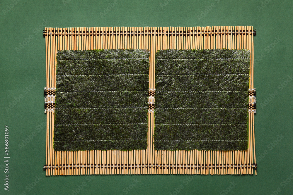 Bamboo mat with nori sheets on color background