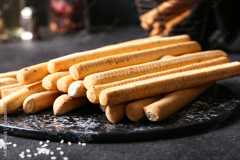 Slate board with tasty Italian Grissini on dark background, closeup