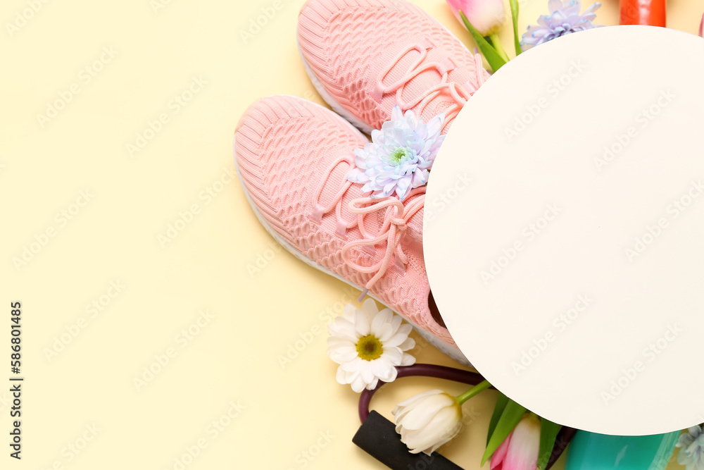 Blank card with sneakers and spring flowers on yellow background, closeup