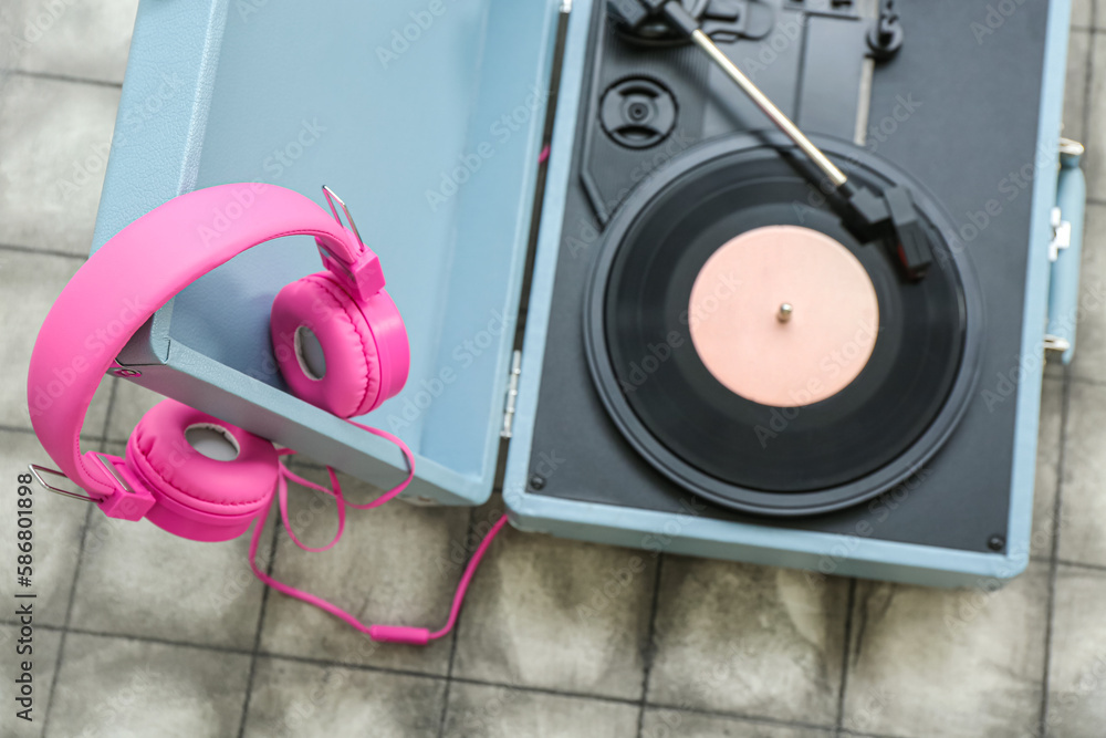 Record player with vinyl disk and headphones on dark tile background, closeup