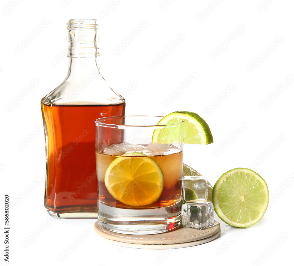 Bottle and glass of cold rum with lime on white background