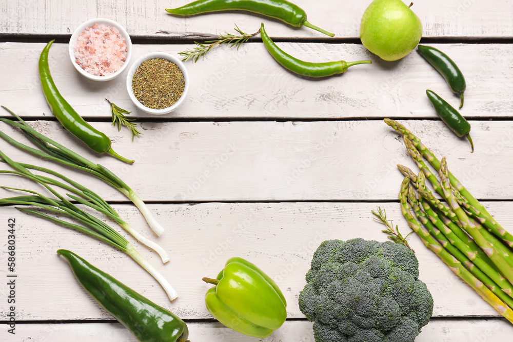 Frame made of different green vegetables on white wooden background