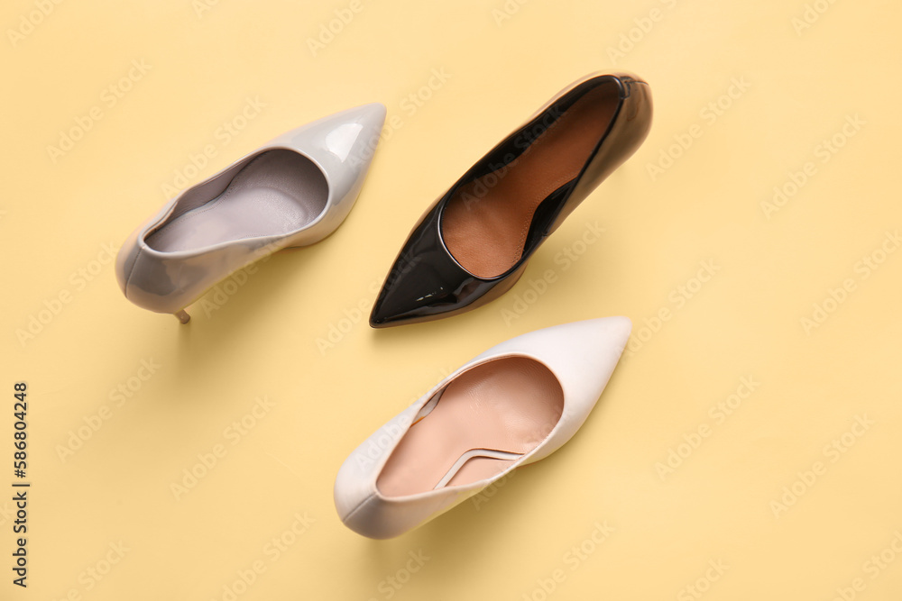 Stylish high heeled shoes on color background, top view