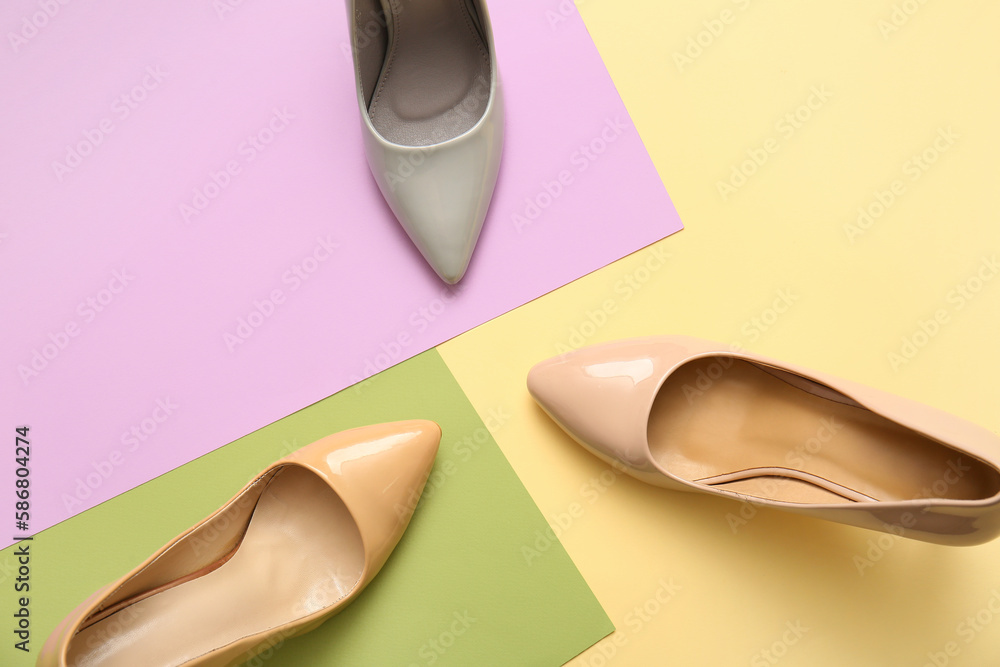 Stylish high heeled shoes on color background, top view