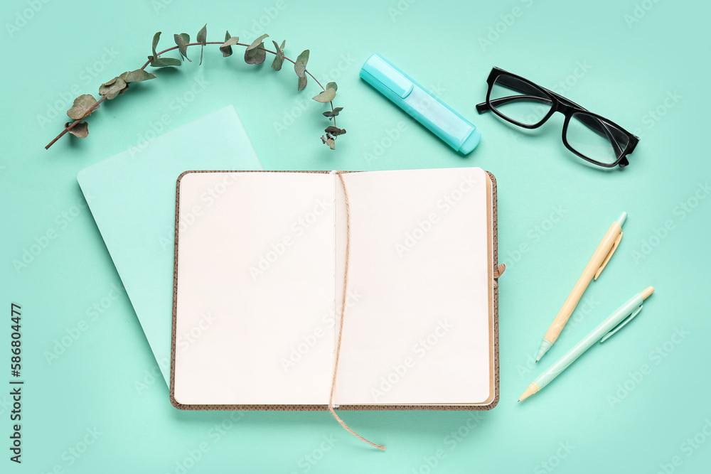 Composition with blank notebook, glasses and pens on turquoise background