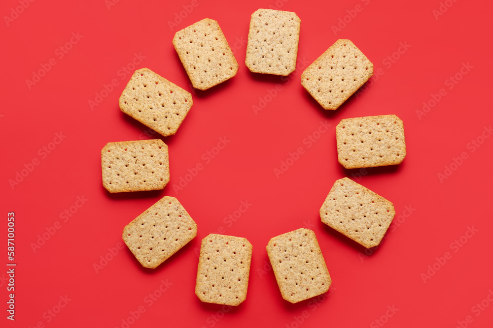 Frame made of tasty crackers on red background