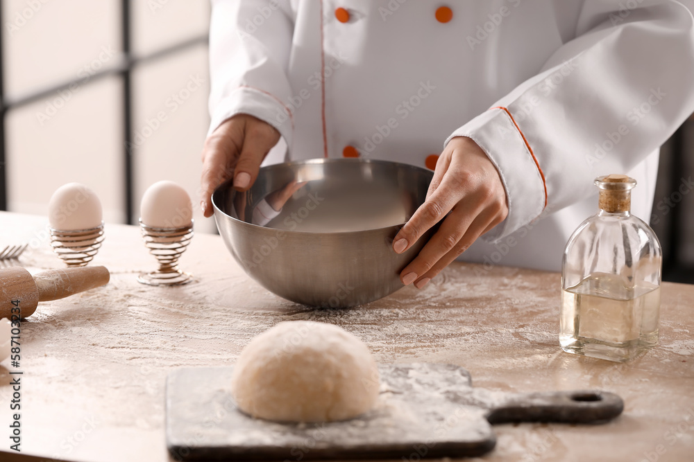 Female chef making dough for pasta at table in kitchen, closeup