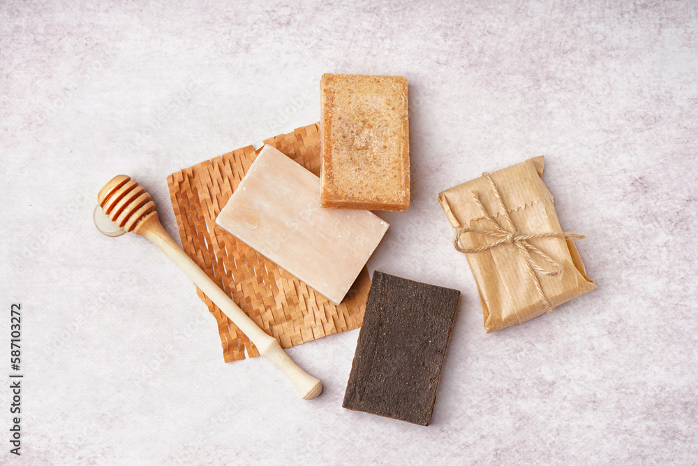 Set of natural soap bars and honey dipper on light background