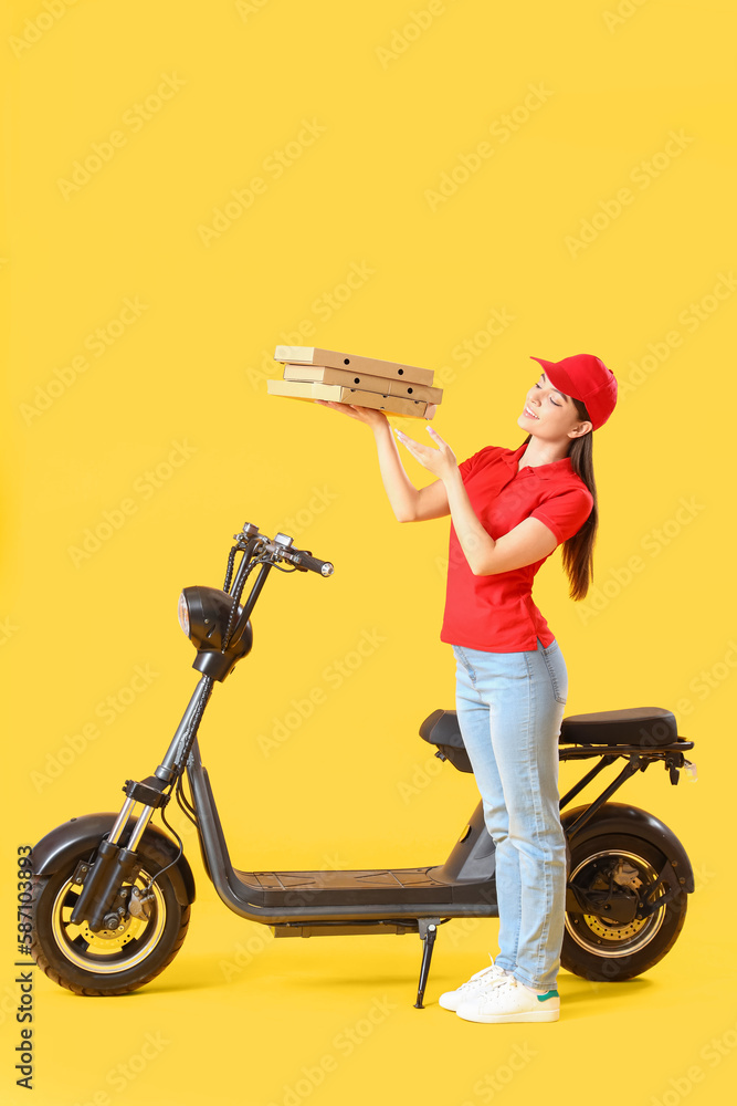 Female courier with scooter and tasty pizza on yellow background