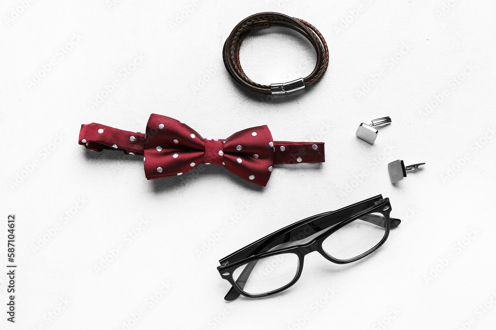 Stylish male bow tie, eyeglasses, cufflinks and bracelet on light background