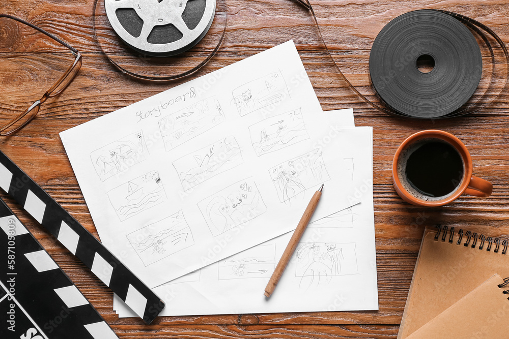 Storyboard with movie clapper, film reel and cup of coffee on wooden background