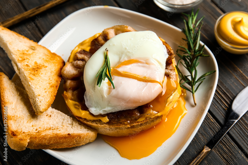 Plate with tasty egg Benedict on dark wooden background