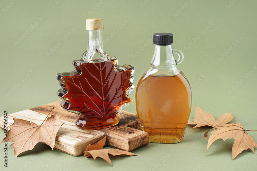 Bottles of maple syrup on green background