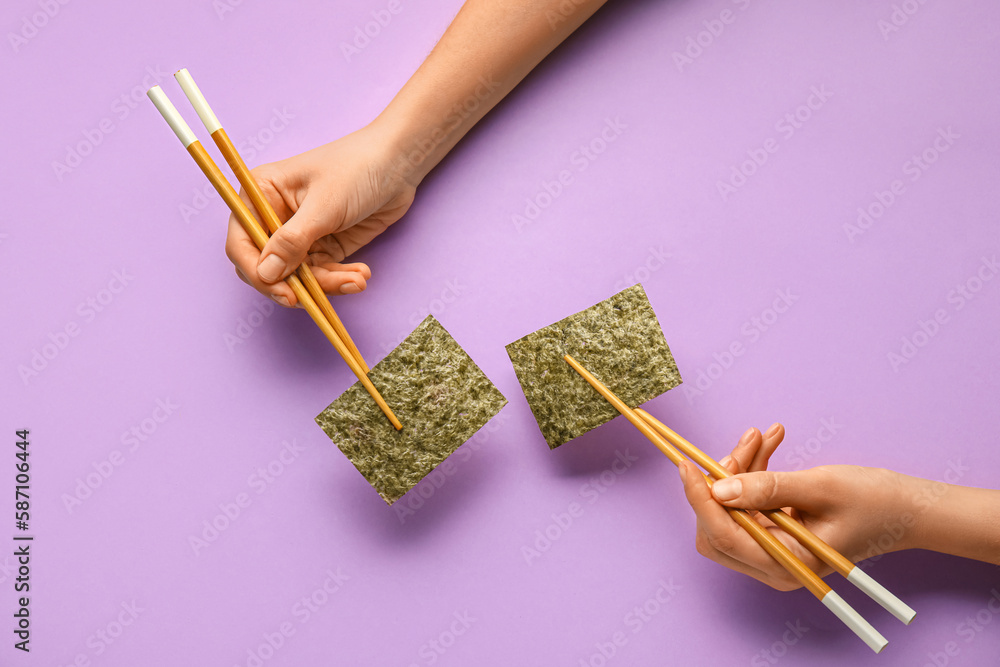 Woman holding chopsticks with nori sheets on color background