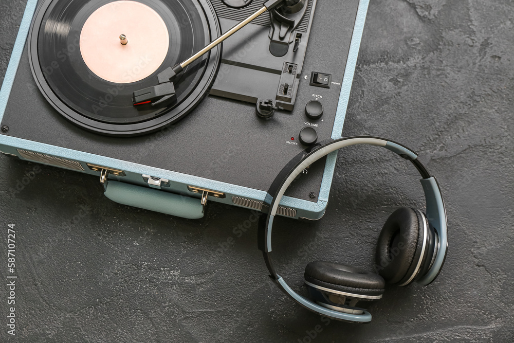 Record player with vinyl disk and headphones on dark background