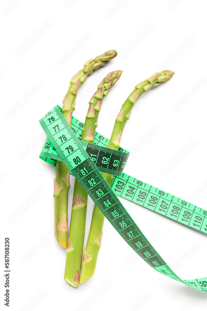 Asparagus and green measuring tape on white background. Diet concept